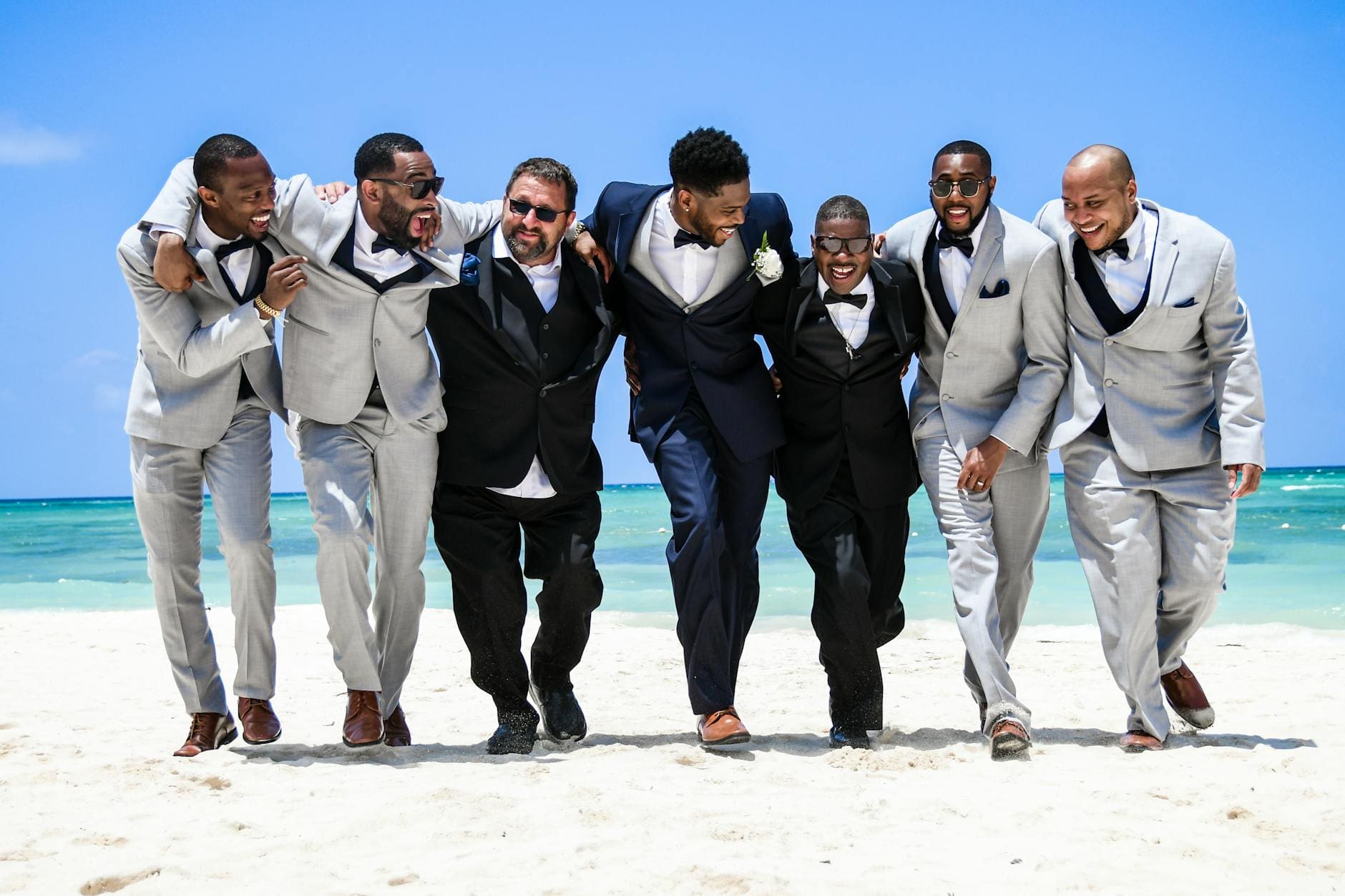 group of men in black suit standing on white sand